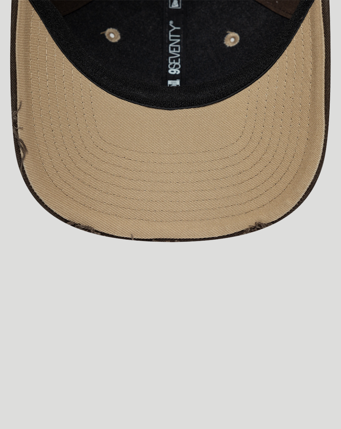 Close up of tan curved brim and black crown with 9SEVENTY label along the interior seam.