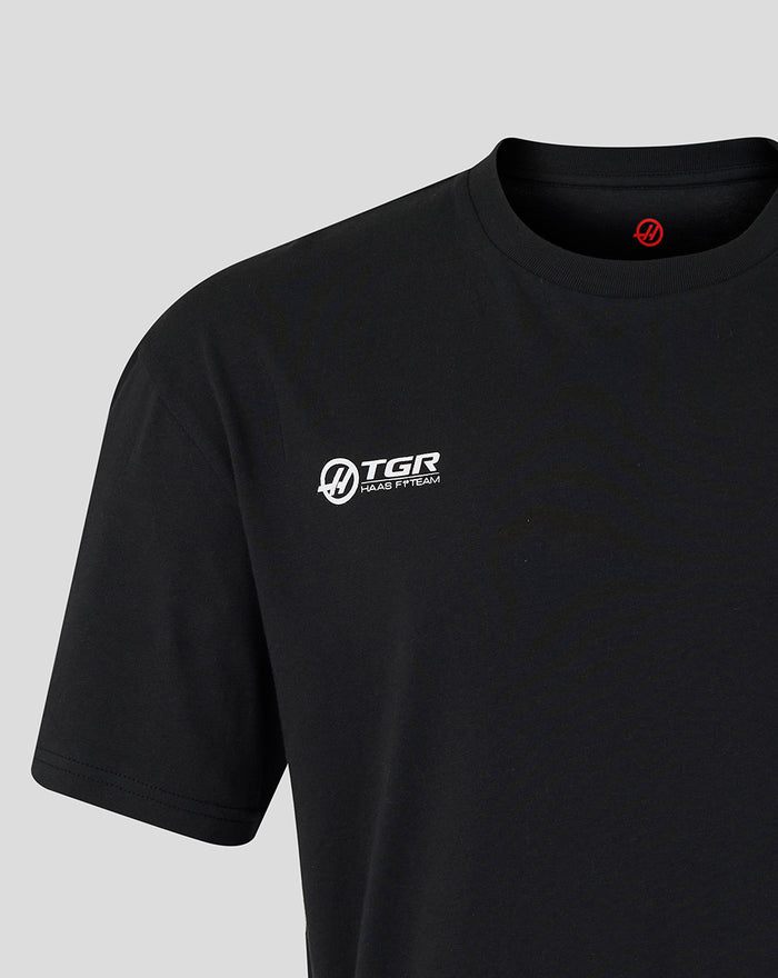 Front of black Haas World Tour T shirt with white left chest TGR Haas F1 Team logo and red collar emblem.