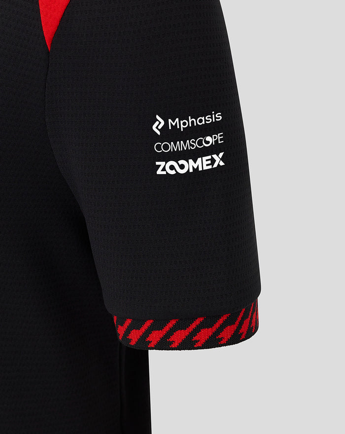 Close up of Haas Team polo sleeve in black with white sponsor logos Mphasis Commscope Zoomex and red trim.