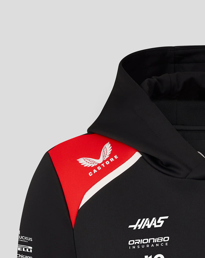 Shoulder area of the hoodie with a red panel featuring the Castore emblem and Haas branding on black fabric.