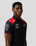 Model wears Official Haas Team Short Sleeve Polo in black with red shoulder panels and front sponsor logos.