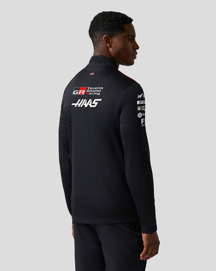 Back view of a male model wearing Haas Team Quarter Zip Midlayer showing large logos on the back and red shoulder panels