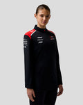 Female model facing forward in Haas Team Quarter Zip Midlayer, black with red shoulder panels and branding on chest and sleeves.