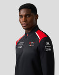 Male model wearing Unisex Official Haas Team Quarter Zip Midlayer in black with red shoulder panels and sponsor logos