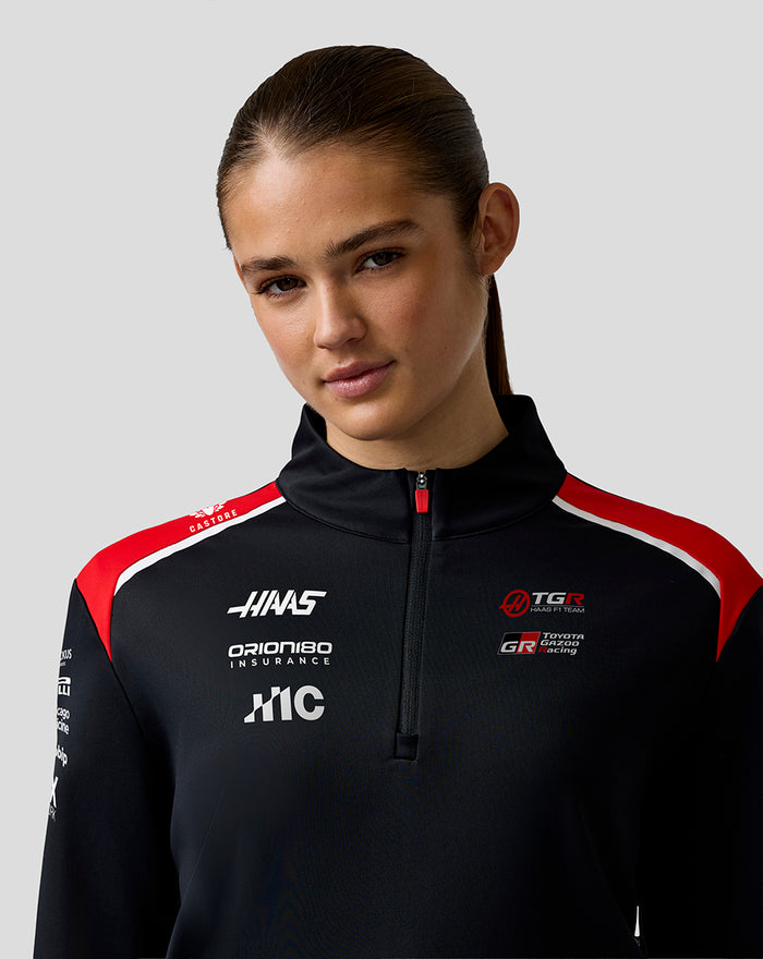 Female model wearing Unisex Official Haas Team Quarter Zip Midlayer with red accents and branding on the chest
