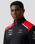 Portrait of a man wearing the Haas Team Soft Shell Jacket in black with red shoulders and branding on the chest.