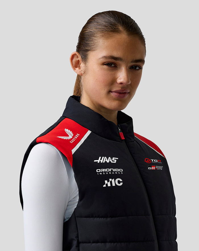 Back view of a female model wearing Official Haas Team Unisex Gilet with black padding and red shoulder panels.