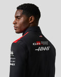 Profile view of a male model wearing Official Haas Team Unisex Gilet, black with red shoulders and back branding.