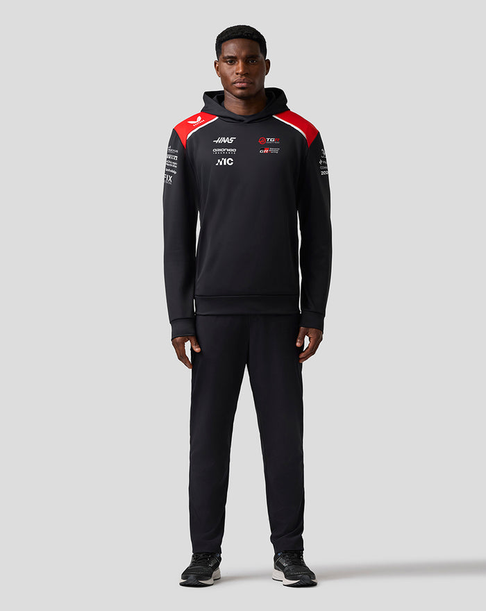 Front view of a black Haas Team pullover hoodie with red shoulder panels and sponsor logos.