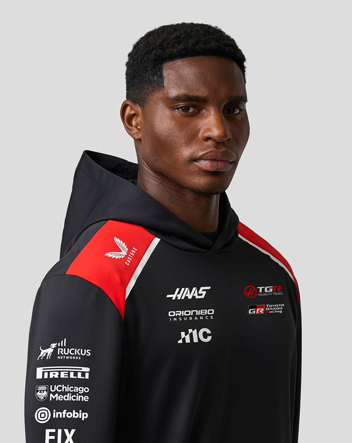 Close up of a male model wearing the Official Haas Team Pullover Hoodie in black with red shoulder panels and branding.