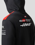 Close-up back view of the hoodie showing a red shoulder panel and sponsor logos on black fabric