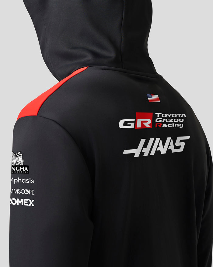 Close-up back view of the hoodie showing a red shoulder panel and sponsor logos on black fabric
