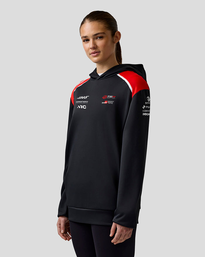 Female model in Official Haas Team pullover hoodie with red shoulders and chest logos.