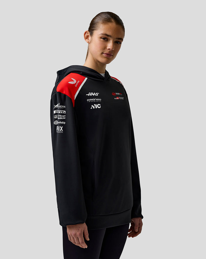 Side angled view of the Haas Team hoodie on a model, highlighting red shoulder panels and chest logos