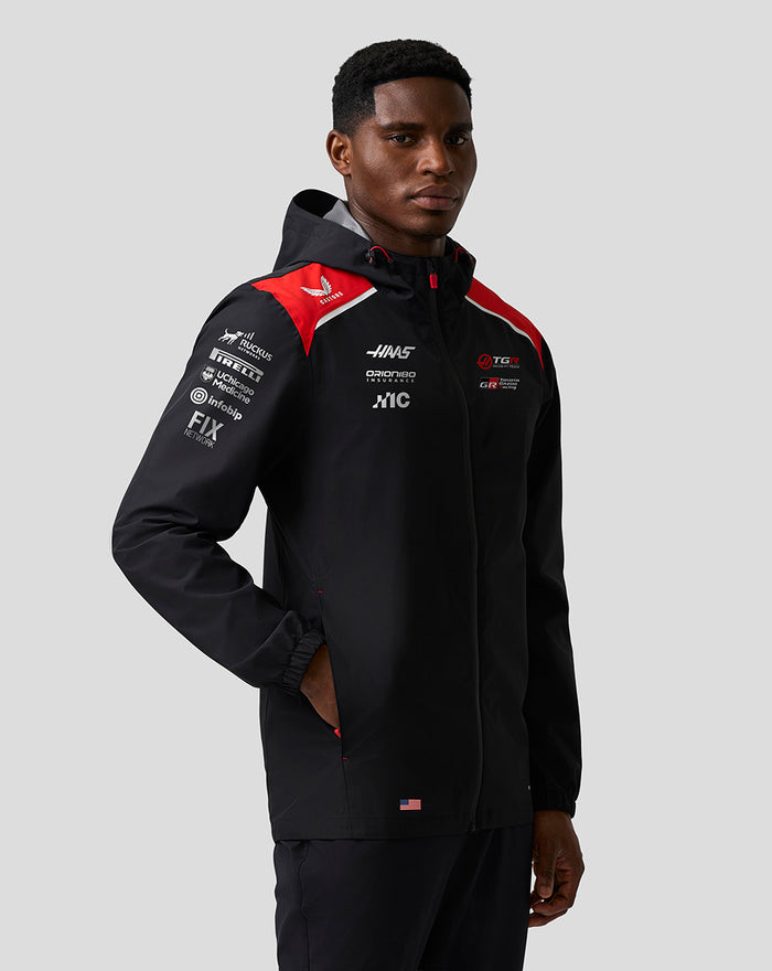 Male model in a black Haas Team water resistant jacket with hood and red shoulder panels; front zip and sponsor logos