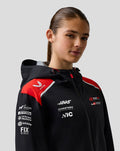 Female model wearing Haas Team water resistant jacket featuring red accents and sponsor logos on the chest and sleeve.