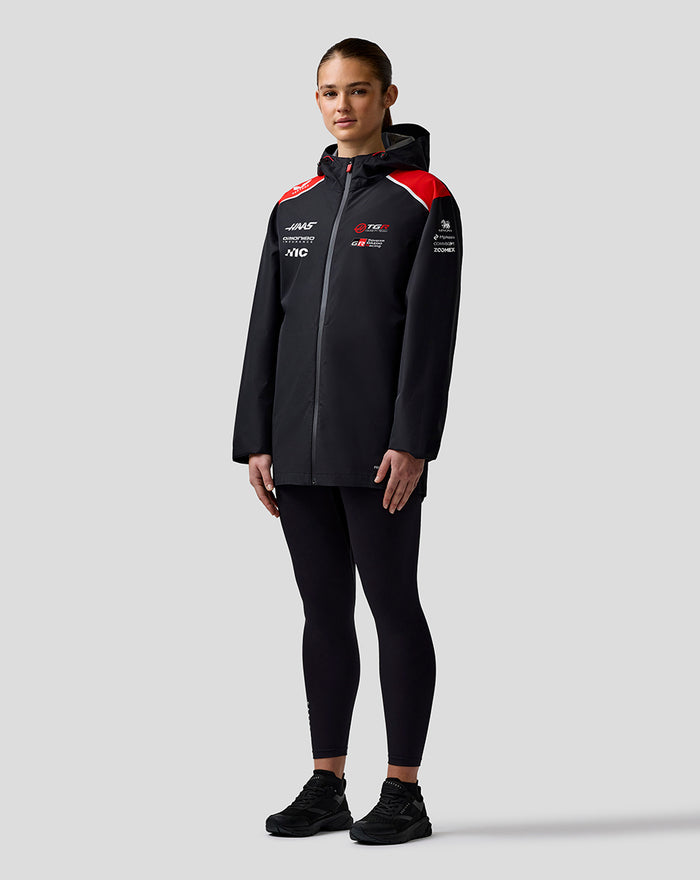 Front view of a model wearing Haas Team water-resistant jacket with hood and red shoulder panels.