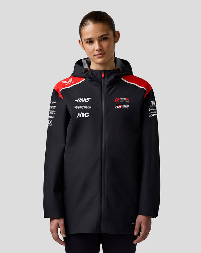 Back view of Haas Team water resistant jacket on a female model, large branding on the back and red shoulder panels.