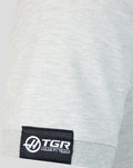 Close-up of sleeve hem with black TGR Haas F1 Team woven label on light gray polo.