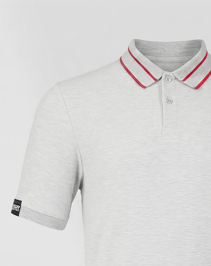 Close up of light grey Haas polo showing a ribbed collar with red stripes and a sleeve label