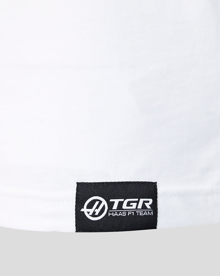 Close up of white T shirt hem with a black woven TGR Haas F1 Team logo label